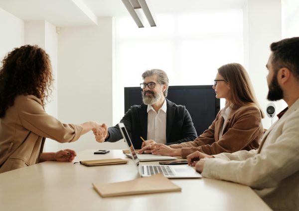 Colleagues in an office celebrating a successful negotiation with a handshake.